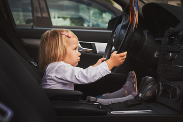 Маленькая девочка сидит за рулем автомобиля