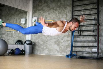 Young athlete man workout in healthy club. Athlete levitates above ground during training.