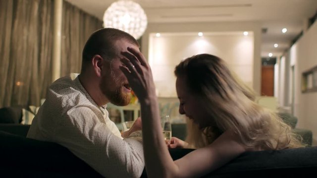 A young couple having fun in the evening, they laugh and drink champagne