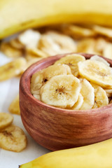 Homemade banana chips (dried and fried banana slices) in wooden bowl