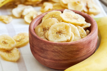 Homemade banana chips (dried and fried banana slices) in wooden bowl
