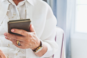 close up image of Senior woman using her mobile phone background.  An idea of modern lifestyle, communication,telecommunication,connectivity, social networking