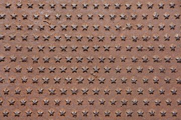 Rusted iron cast panel covered with five-pointed stars pattern.