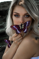 Young beautiful woman with butterfly in curly blond hair.