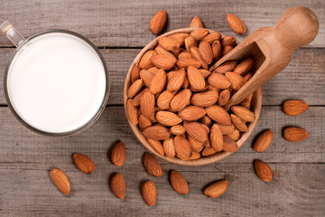 Almond milk in a glass and almonds in a bowl on old wooden background. Top view