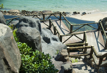 Stairs from the mountain slope to the sandy beach by the sea.