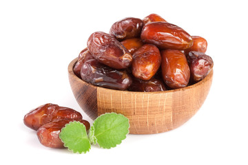 Dates in a wooden bowl with a mint leaf isolated on white background
