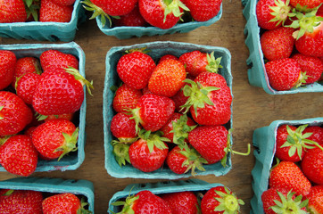 Strawberries displayed in baskets for market on wooden table - Powered by Adobe