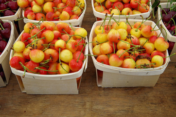 Cherries displayed in baskets for market on wooden table