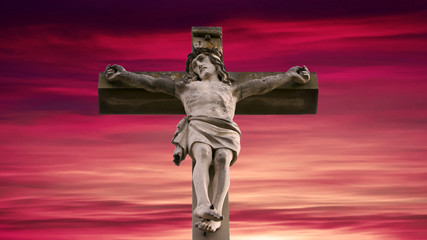 stone cross with Jesus and red sky