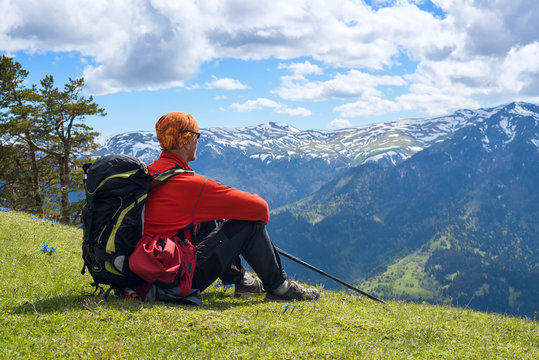 Man adventurer sits on the alpine meadow among the wildflowers
