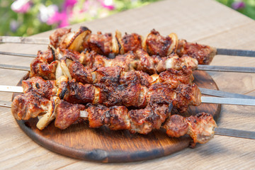 Grilled pork on skewers roasted on the grill on wooden chopping board