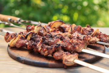 Grilled pork on skewers roasted on the grill on wooden chopping board