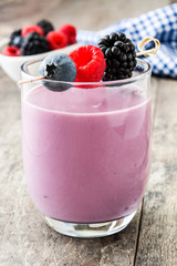 Fototapeta na wymiar Healthy berry smoothie in glass on wooden table 
