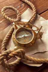 Compass and rope on wooden table. close up