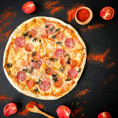 Italian tasty pizza and spices on dark background. Flat lay, top view.