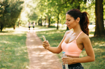 Fit young woman using a cell phone outdoors, healthy lifestyle