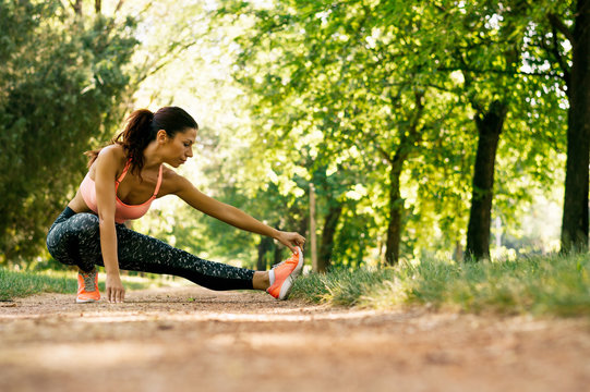 Young fitness woman runner stretching legs before run