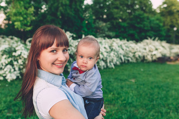 Portrait of a woman carrying little son at the park