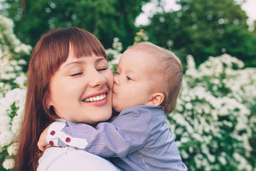 happy little boy kissing mother outdoors