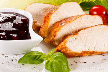 Roast chicken breast and vegetables on white background