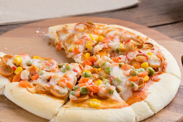 pizza with seafood in wooden plate on wooden table