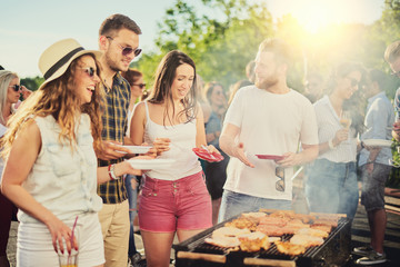 Friends having outdoor party and eating barbecue - obrazy, fototapety, plakaty