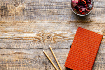 composition of orange notebook with flower sachets on wooden tab