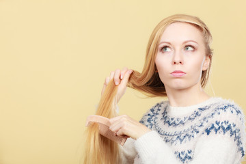 Teenage blonde girl brushing her hair with comb