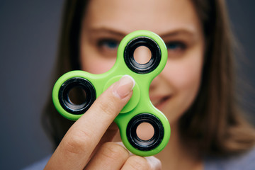 Beautiful young woman on a gray background holds a spinner