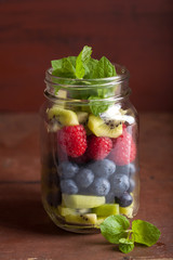 Fototapeta na wymiar fruit salad in mason jar strawberry blueberry kiwi apple mint