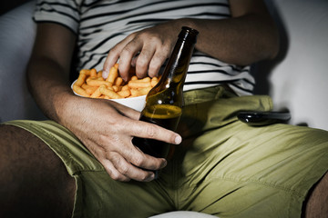 man drinking beer and eating cheese puffs