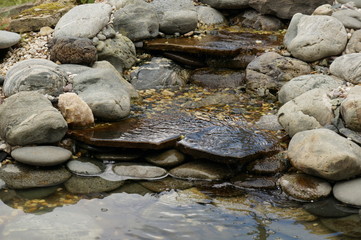 A small stone waterfall with several rapids and clear transparent spring water