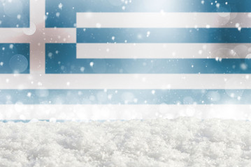 Defocused Greece flag as a winter Christmas background with falling snow, snowdrift and bokeh