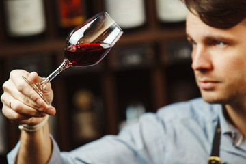 Bokal of red wine on background, male sommelier appreciating drink