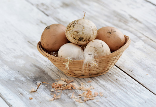œufs fraîchement pondus dans petit panier sur table en bois blanc