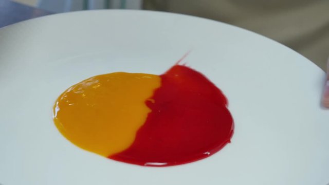 Smearing jam on a plate. Two kinds of jam smeared on the plate with a spatula.