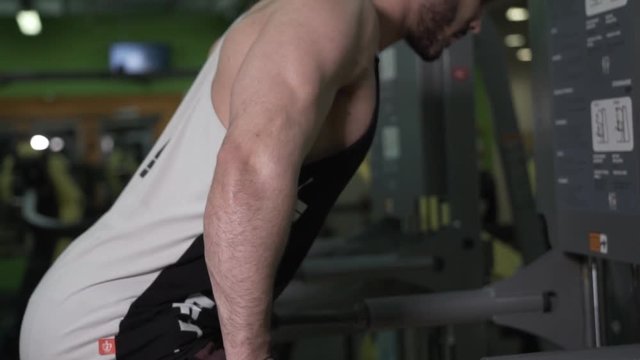 Closeup of Muscular Man Doing Triceps Exercise on Parallel Bars in Gym.