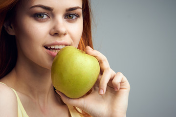 Beautiful young woman on a gray background holding an apple