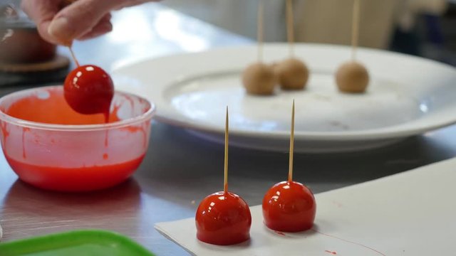Woman dipping candy apple into bowl with caramel.