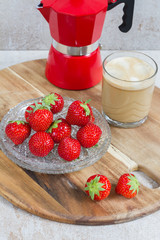 Coffee, Espresso maker and strawberries on beige background. Red espresso maker. Fresh strawberries on glass plate. 

