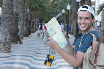 Joyful tourist holding map and camera during a vacation