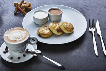 Cheese pancake with coffee and seabuckthorn sauce, in a plate on the table