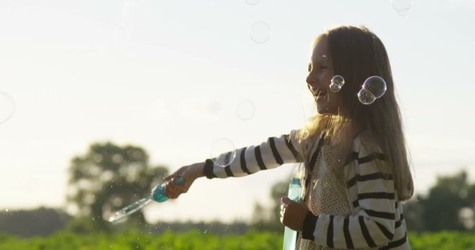 Air Bubbles in Hands of Little Girl Playing Outdoors