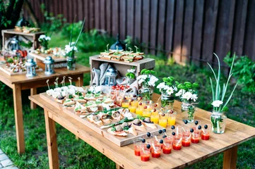 Photo sur Plexiglas Buffet, Bar Belle table de buffet de banquet de restauration décorée dans un style rustique dans le jardin. Différentes collations, sandwichs et cocktails. Extérieur.