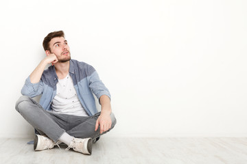 Pensive man sitting on floor and looking upwards