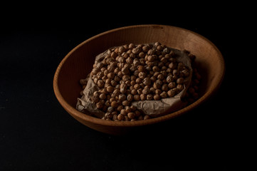 Grains of raw chickpeas in a wooden pot on on dark surface background