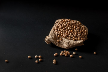 Grains of raw chickpeas in a wooden pot on on dark surface background