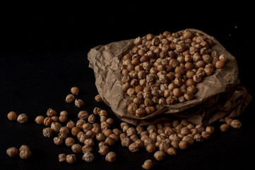 Grains of raw chickpeas in a wooden pot on on dark surface background