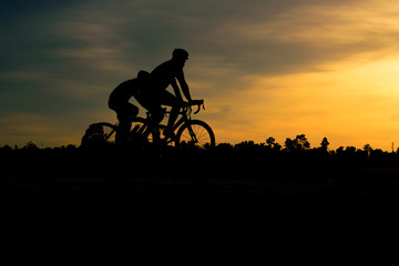 Silhouette of cyclist riding   bike on road at sunset.